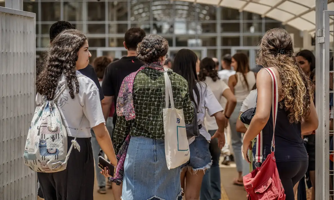 Imagem diversos alunos em frente a uma escola